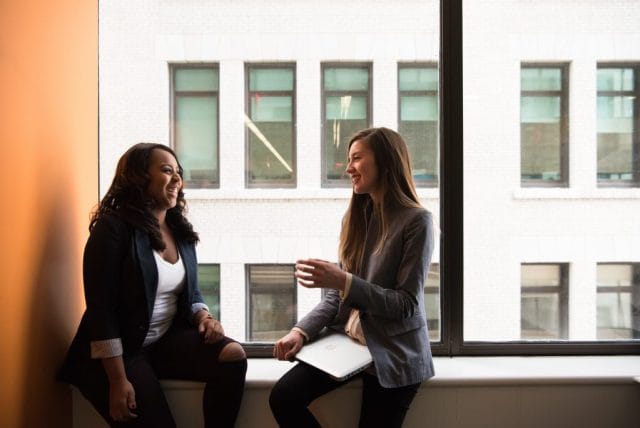 two woman sitting by the window laughing app development small business